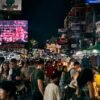 a crowd of people walking down a street next to tall buildings